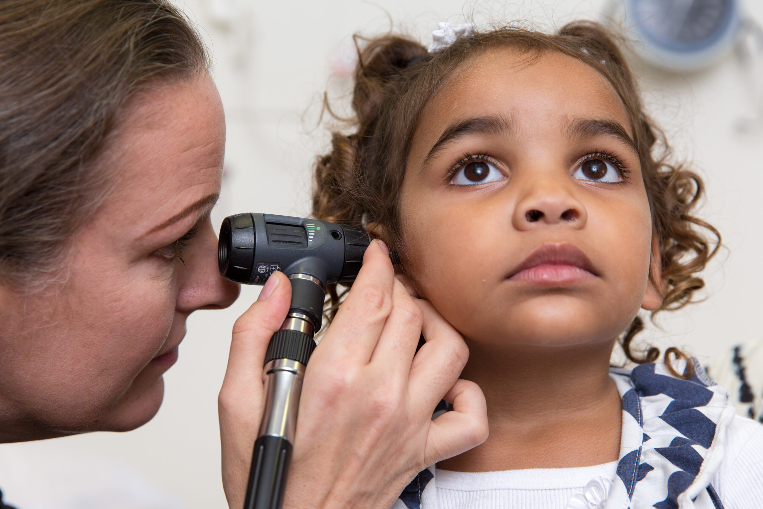 Paediatrician looking into Aboriginal girlâÂs ear